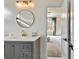 Bathroom vanity with grey cabinets, stone countertop, and a round mirror, with an attached bedroom at 2634 Greenes Ln, Powder Springs, GA 30127