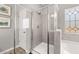 Modern tiled shower room with glass doors next to a tub and patterned window, illuminated by recessed lights at 2720 Ravencliff Dr, Austell, GA 30168