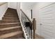 Carpeted staircase with dark wrought iron spindles and open view of the kitchen at 2720 Ravencliff Dr, Austell, GA 30168