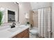 A bathroom with warm wood vanity, a marble countertop, and a shower/tub combination with neutral curtain at 15 York Trce, Cartersville, GA 30121