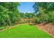 Lush green backyard with a well-maintained lawn, mature trees, and a charming wooden fence under a sunny sky at 57 Moury Se Ave, Atlanta, GA 30315