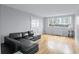 A modern living room with hardwood floors and a black sofa features natural light from a large window at 215 Piedmont Ave # Apt 402, Atlanta, GA 30308