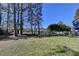 Large, fenced-in backyard featuring mature trees with a clear blue sky at 3736 Rainbow Cir, Snellville, GA 30039