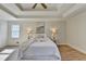 Bright main bedroom with a tray ceiling, neutral walls, wood-look flooring, and a large window at 3736 Rainbow Cir, Snellville, GA 30039