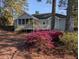 View of the rear exterior of the home, featuring an enclosed porch and beautifully landscaped yard with flowering bushes at 4020 Winchester Way, Loganville, GA 30052