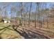 A view of the wooded area, featuring a well-maintained lawn, mature trees, and additional outdoor storage shed at 218 Sutallee Ridge Ne Ct, White, GA 30184