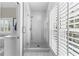 All-white shower with glass doors, rainfall showerhead, and bright natural light from the window at 105 Leisure Trl, Peachtree City, GA 30269
