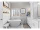 Bright bathroom featuring a soaking tub, marble tile, and stylish vanity with natural light from the window at 105 Leisure Trl, Peachtree City, GA 30269