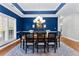 Elegant dining room with wainscotting, a tray ceiling, modern chandelier, and access to the kitchen and backyard at 105 Leisure Trl, Peachtree City, GA 30269
