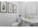 Elegant powder room with pedestal sink, gold faucet, and leaf-themed artwork at 1029 Emory Parc Pl, Decatur, GA 30033