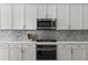 White cabinets, stainless steel appliances, and a mosaic backsplash make for a wonderful kitchen area at 1029 Emory Parc Pl, Decatur, GA 30033