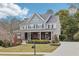 Two-story home with gray siding, brick accents, covered porch, manicured landscaping, and long driveway at 2064 Democracy Dr, Buford, GA 30519