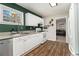 Cozy kitchen with green accent wall, white cabinets, wood-look flooring, and stainless steel dishwasher at 2302 Abner Nw Pl, Atlanta, GA 30318