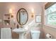 Stylish bathroom with pink walls, pedestal sink, decorative mirror, sconce lighting and storage shelves at 306 Nelms Ne Ave, Atlanta, GA 30307