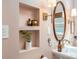 Close up of bathroom with pink walls, built in shelves, oval mirror, sconce lighting and pedestal sink at 306 Nelms Ne Ave, Atlanta, GA 30307