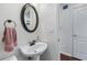 Cozy powder room with a decorative mirror, a pedestal sink, and a neutral color scheme at 565 Ashvale Overlook, Alpharetta, GA 30005