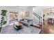 Cozy living room featuring a gray sofa, side table, and a plant next to the staircase at 565 Ashvale Overlook, Alpharetta, GA 30005