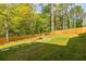 Large backyard with green lawn surrounded by a wooden fence and mature trees, featuring a stone walkway at 783 Phil Haven Ln, Kennesaw, GA 30152