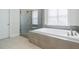 Large bathtub with a glass enclosed shower and tiled flooring at 783 Phil Haven Ln, Kennesaw, GA 30152