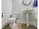 Charming powder room featuring a pedestal sink, round mirror, and wood look flooring at 783 Phil Haven Ln, Kennesaw, GA 30152