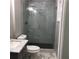 Modern bathroom with a marble shower enclosure with glass door, toilet, and gray vanity at 1140 Smith Sw St, Atlanta, GA 30310