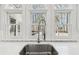 A stainless steel sink with a modern faucet is set beneath a row of arched windows offering a view of the trees outside at 6030 Chimney Springs Rd, Buford, GA 30518