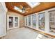 A sunroom offers views of the lake through multiple windows, wood paneled ceilings, brick accent walls, and tile flooring at 6030 Chimney Springs Rd, Buford, GA 30518