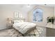 Staged main bedroom featuring a large arched window, lamps, and decorative pillows at 302 Gladstone Dr, Mcdonough, GA 30253