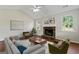 Cozy living room features a stone fireplace, hardwood floors, a ceiling fan, and lots of natural light at 217 Crystal Ct, Hampton, GA 30228