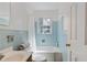 Clean bathroom features a blue tiled wall, white fixtures, tub-shower, and natural light at 6275 Hunting Creek Rd, Atlanta, GA 30328