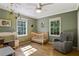 Bedroom with wood floors, a crib, and a comfortable chair, illuminated by natural light from the windows at 6275 Hunting Creek Rd, Atlanta, GA 30328