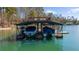 Covered boat dock featuring two boat slips with boats, storage, and an upper deck for relaxing by the water at 7565 Heard Rd, Cumming, GA 30041