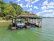 Exterior view of a covered boat dock featuring boat slips, an upper deck, and ladder access to the lake at 7565 Heard Rd, Cumming, GA 30041