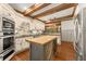 Kitchen featuring a butcher block island, stainless steel appliances, custom cabinets, and wood beam ceilings at 7565 Heard Rd, Cumming, GA 30041