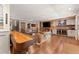 Living room featuring hardwood floors, custom bar, stone fireplace, and game table at 7565 Heard Rd, Cumming, GA 30041