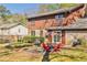 A brick and wood sided house with a stone patio in the backyard with a grill and seating at 571 Tahoe Cir, Stone Mountain, GA 30083