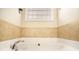 Close-up of a tiled bathtub with chrome fixtures and a window at 8000 Abington Dr, Locust Grove, GA 30248