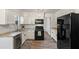 Well-lit kitchen featuring white cabinets, black appliances, and modern wood flooring at 9635 Loblolly Ln, Roswell, GA 30075