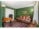Well-lit home office with green walls, a classic wooden desk, and a comfortable leather sofa at 9635 Loblolly Ln, Roswell, GA 30075