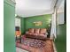 Well-lit home office with green walls, a classic wooden desk, and a comfortable leather sofa at 9635 Loblolly Ln, Roswell, GA 30075
