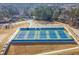 Aerial view of community tennis courts with lighting and fencing, with trees and houses in the background at 1830 Greystone Ct, Marietta, GA 30068