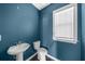 Cozy powder room featuring a pedestal sink, toilet, and a window with white blinds and a blue accent wall at 2028 Holtz Ln, Atlanta, GA 30318