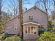 Rear view of a beautiful home featuring a sunroom, surrounded by foliage and mature trees at 566 Hickory Hills Ct, Stone Mountain, GA 30083