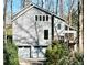 Two-story home featuring vertical siding, large windows, and an attached two-car garage, nestled amongst mature trees at 566 Hickory Hills Ct, Stone Mountain, GA 30083