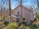 A serene rear view of the home with a sunroom addition nestled in a wooded setting at 566 Hickory Hills Ct, Stone Mountain, GA 30083