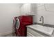 This laundry room has a sink and red washer dryer set in a simple space, with white cabinets for extra storage at 108 Brighton Blvd, Woodstock, GA 30188