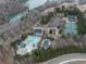 Aerial view of community amenities, featuring a pool, clubhouse, tennis courts, and parking near a lake at 214 White Cloud Run, Canton, GA 30114