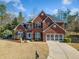 Charming two-story brick home featuring a well-manicured lawn and attached two car garage at 214 White Cloud Run, Canton, GA 30114