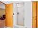 Bathroom with glass shower enclosure, wood doors, and a glimpse of the red chair in the other room at 2499 E Maddox Rd, Buford, GA 30519