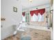 Bathroom with large bathtub, window, red valance, marble floors, white fixtures, and framed picture at 2499 E Maddox Rd, Buford, GA 30519